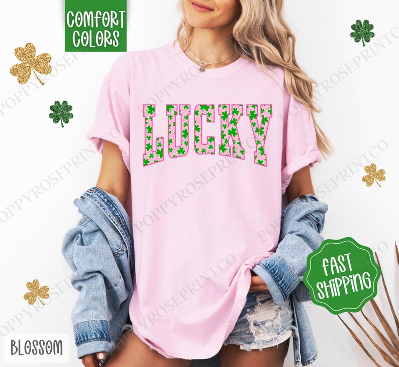 May include: Pink t-shirt with the word "LUCKY" in green and pink letters. The letters are filled with a pattern of green shamrocks.