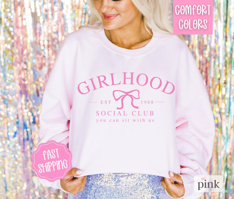 May include: Pink cropped sweatshirt with the text "GIRLHOOD EST 1988 SOCIAL CLUB you can sit with us" and a pink bow.