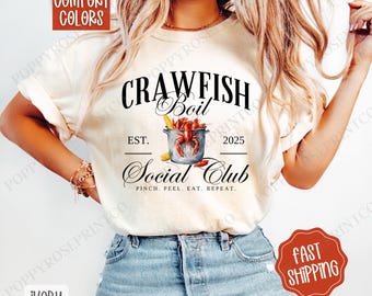 Puede incluir: Una camiseta blanca con un diseño gráfico en negro y rojo que dice "Crawfish Boil Social Club Est. 2025 Pinch. Peel. Eat. Repeat."