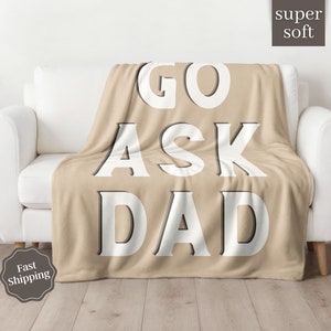 May include: A tan fleece throw blanket with the text "GO ASK DAD" in white letters.