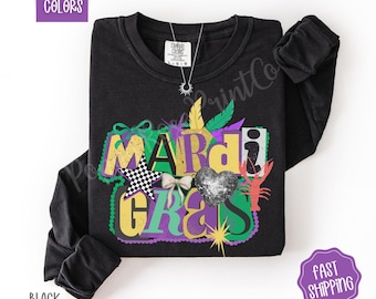 May include: Black long-sleeve shirt with a colorful "Mardi Gras" graphic. The design includes a checkered star, a sequined heart, a bow, and a crawfish. The shirt has the words "Comfort Colors" printed on the top left.