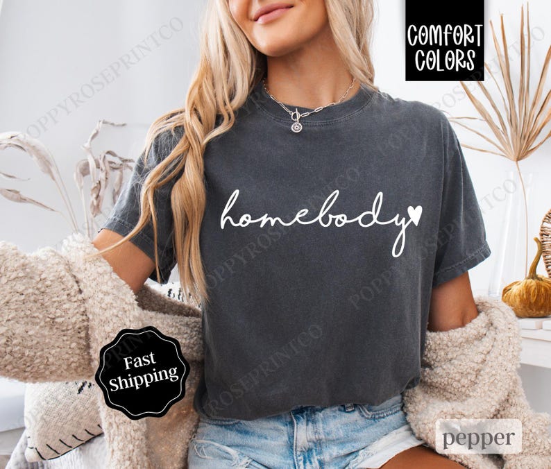 May include: A dark gray t-shirt with the text "homebody" in white with a small white heart after the word "body".