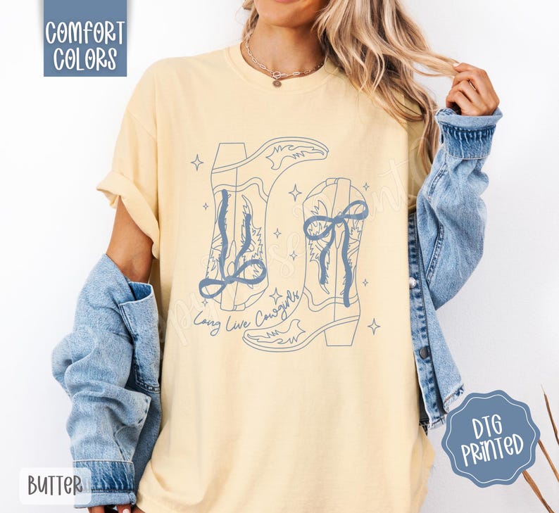 May include: Butter yellow t-shirt with a light blue graphic of two cowboy boots and the text "Long Live Cowgirls." The shirt also has the words "Comfort Colors" and "DTG Printed" printed on it.