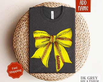 May include: Dark grey heather t-shirt featuring a yellow softball bow with red stitching. The bow has the name Addison written on it.