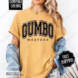 May include: A mustard yellow t-shirt with black text that reads "GUMBO WEATHER".