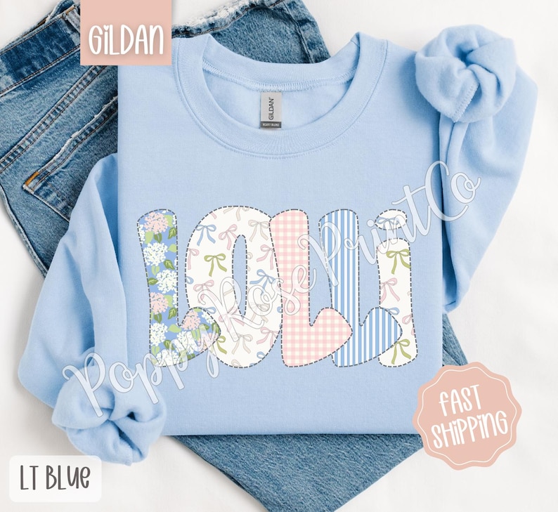 May include: Light blue sweatshirt with the name "Lolli" spelled out in colorful patchwork letters. The letters are made of different fabrics with floral, gingham, and striped patterns.