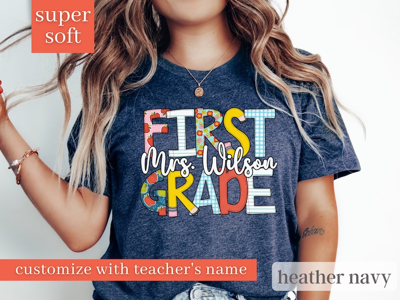 May include: A heather navy blue t-shirt with the text "First Grade" in colourful, patterned letters. The text "Mrs. Wilson" is included in the design.
