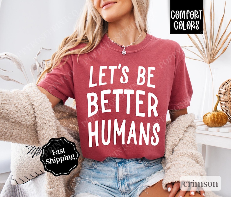 May include: A crimson red t-shirt with the text "Let's Be Better Humans" printed in white.