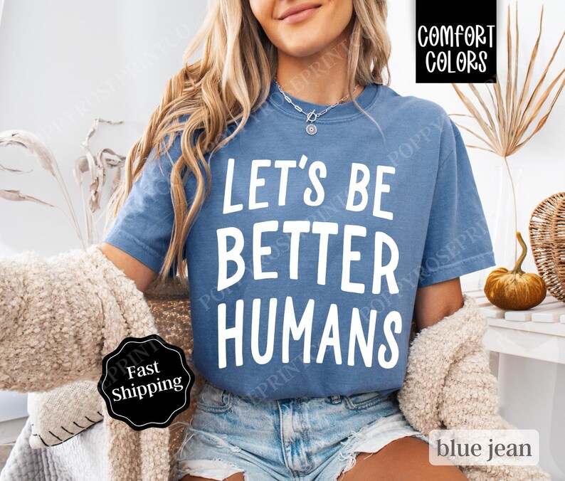 May include: A blue jean t-shirt with the text "Let's Be Better Humans" in white lettering.