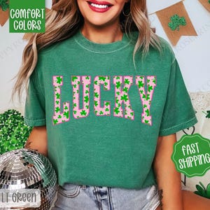 May include: Green t-shirt with the word "LUCKY" printed in pink letters. The letters are filled with a pattern of green shamrocks.