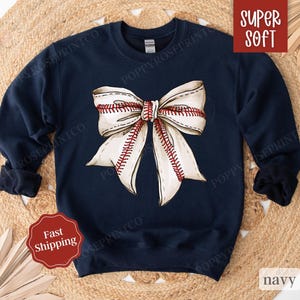 May include: Navy blue sweatshirt with a white baseball-themed bow. The sweatshirt is super soft and has the words "Super Soft" printed on the top right corner.