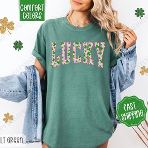 May include: A green t-shirt with a pink "LUCKY" graphic. The graphic is made up of green shamrocks.