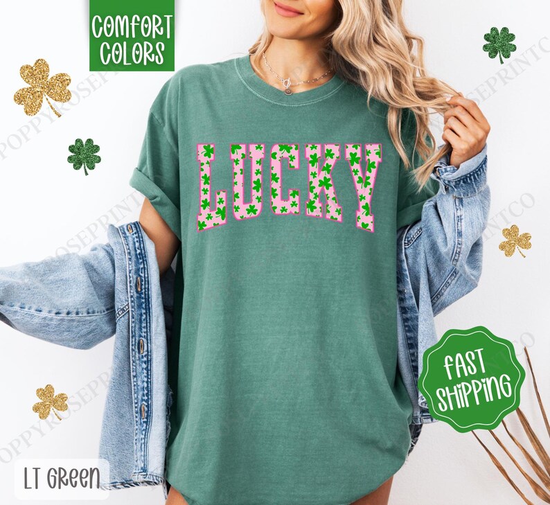 May include: A green t-shirt with a pink "LUCKY" graphic. The graphic is made up of green shamrocks.