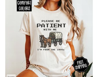 Puede incluir: Una camiseta blanca con el texto "Por favor, ten paciencia conmigo, soy de los años 1900" y una imagen pixelada de un carro tirado por caballos.