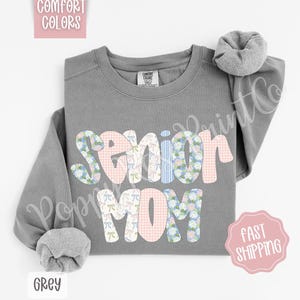 May include: Gray sweatshirt with the text "Senior Mom" in colorful patchwork letters. The letters are decorated with floral patterns and bows.