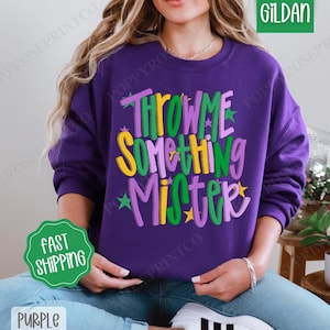 May include: Purple sweatshirt with the text "Throw Me Something Mister" in green, yellow, and purple lettering with stars.