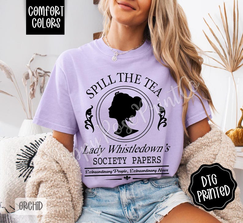 Pu&ograve; includere: Una maglietta lilla con la scritta "SPILL THE TEA" e "Lady Whistledown's SOCIETY PAPERS" in nero. Il design include la silhouette di una donna in un cerchio. La maglietta presenta anche le parole "COMFORT COLORS" e "DTG PRINTED".