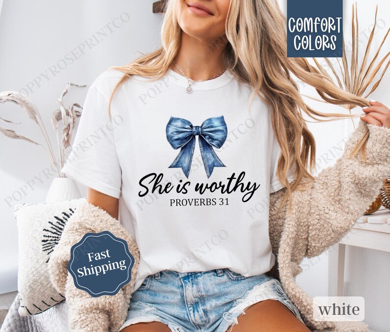 May include: White t-shirt with a blue denim bow and the text "She is worthy Proverbs 31" printed on the front.