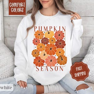 May include: White sweatshirt with a graphic design of orange and brown pumpkins with the text "Pumpkin Season".