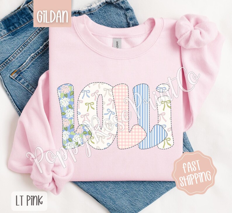 May include: A light pink Gildan sweatshirt with the word "LOLI" spelled out in colorful patchwork letters. The letters are made of different fabrics with floral, gingham, and striped patterns.
