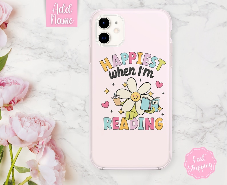 May include: A pink iPhone case with a daisy holding a book and a cup of coffee. The text on the case reads "Happiest when I'm reading".