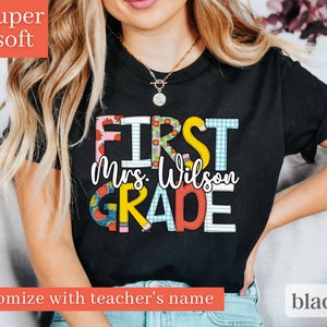 May include: Black t-shirt with the text "First Mrs. Wilson Grade" in colourful letters with a checkered, polka dot, and apple design.  Customise with teacher's name.