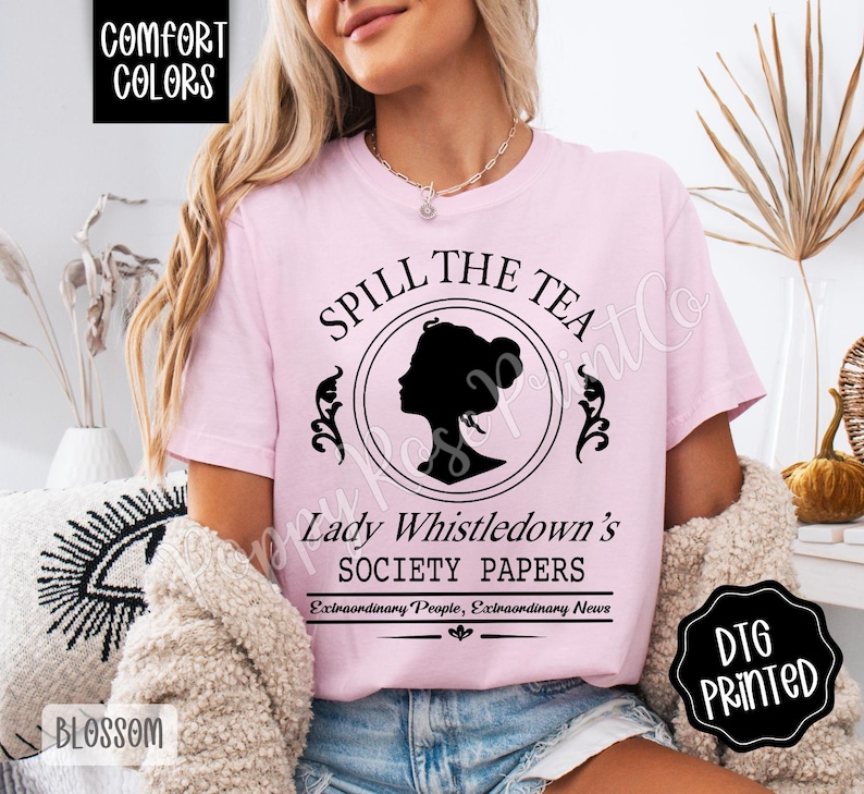 Pu&ograve; includere: T-shirt rosa chiaro con la scritta "SPILL THE TEA" sopra una silhouette nera del profilo di una donna. Sotto la silhouette, il testo recita "Lady Whistledown's SOCIETY PAPERS". La maglietta ha anche il testo "Extraordinary People, Extraordinary News".