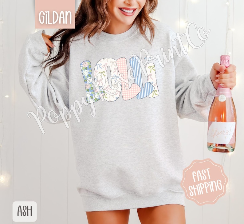 May include: A gray sweatshirt with the word "Lola" spelled out in colorful patchwork letters. The letters are made of different fabrics with floral, plaid, and gingham patterns.