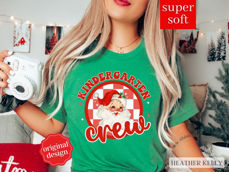 May include: Green t-shirt with a red and white checkered circle featuring a cartoon Santa Claus and the text "Kindergarten Crew".