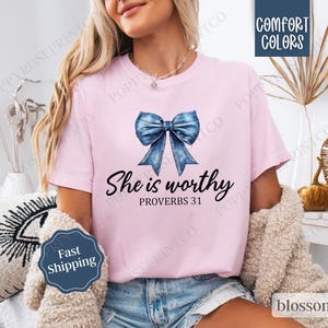 May include: A pink t-shirt with a blue denim bow and the text "She is worthy Proverbs 31" printed on the front.