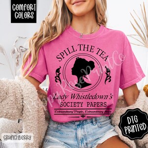 Pu&ograve; includere: Una maglietta Comfort Colors rosa con la scritta "Spill the Tea" e la silhouette del profilo di una donna. La maglietta presenta anche la scritta "Lady Whistledown's Society Papers" e "Extraordinary People, Extraordinary News."
