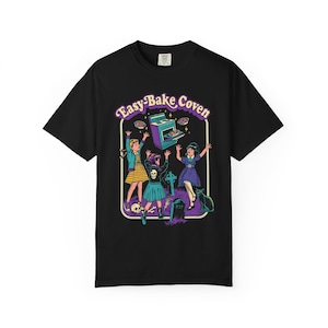 May include: Black t-shirt with a graphic featuring three cartoon witches, an oven, and a black cat. The text "Easy-Bake Coven" is arched above the image in purple and yellow.