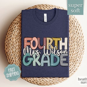 May include: A heather navy blue t-shirt with the text "FOURTH Mrs. Wilson GRADE" in colorful, hand-drawn lettering.