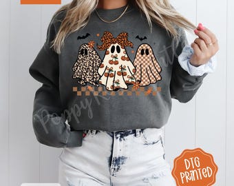 May include: Dark gray sweatshirt featuring three ghost characters with different patterns and designs. The ghosts have a leopard print, cherry, and checkered pattern. The text "Comfort Colors" and "DTG Printed" are visible.