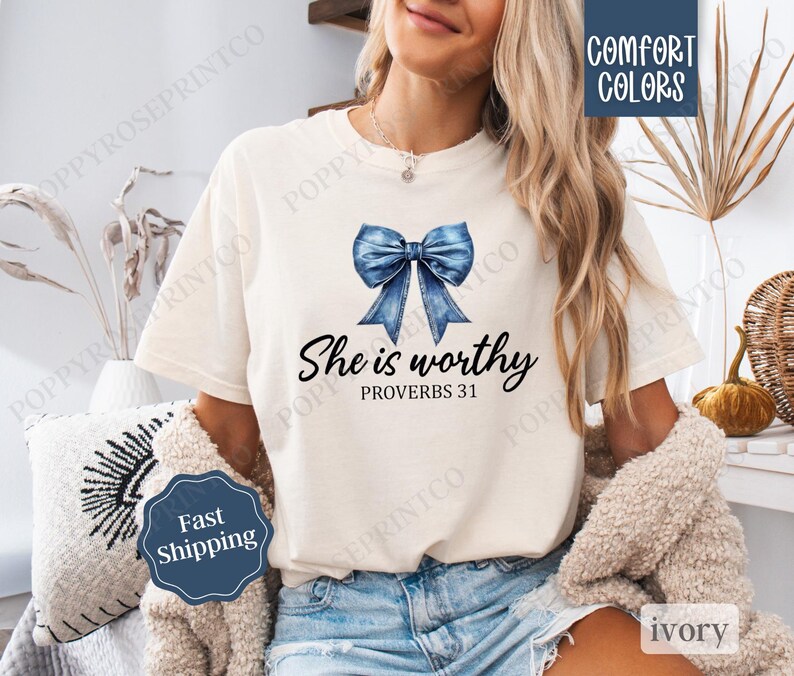 May include: A white t-shirt with a blue denim bow and the text "She is worthy Proverbs 31" printed on it.