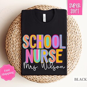 Puede incluir: Camiseta negra con el texto "SCHOOL NURSE Mrs. Wilson" en letras coloridas y divertidas. La camiseta est&aacute; hecha de tela s&uacute;per suave.