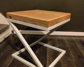 Könnte beinhalten: Ein kleiner Holztisch mit einem weißen Metallgestell. Der Tisch hat eine rechteckige Tischplatte und ein schlichtes Design.