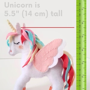 The finished 5.5-inch felt unicorn toy held in a hand to demonstrate its small, huggable size.
