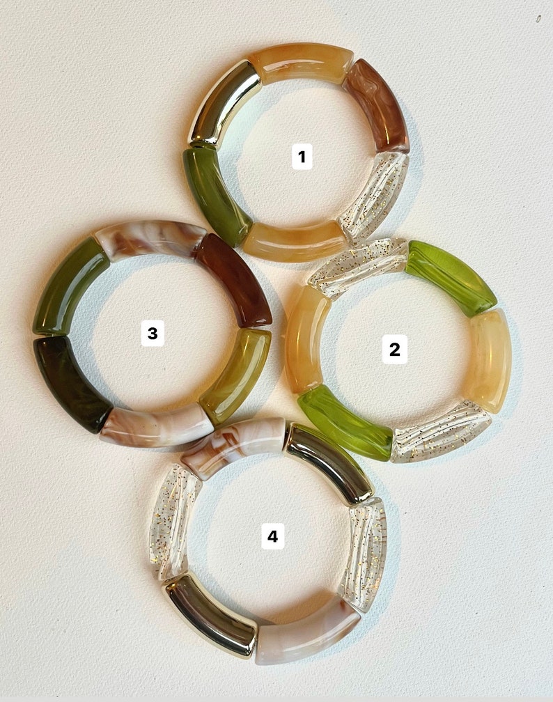 Pu&ograve; includere: Quattro braccialetti colorati realizzati con diversi materiali, tra cui trasparente, marrone, verde e oro. Ogni braccialetto ha un numero da 1 a 4.