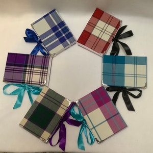 May include: Six rectangular journals arranged in a circle, each featuring a unique plaid fabric cover in colors including blue, red, purple, teal, and green. Each journal has silver-toned metal corner protectors and a decorative satin ribbon tie.