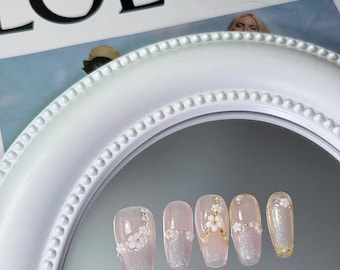 Roze glitterpers op de nagels met gouden vlokken en bloemen