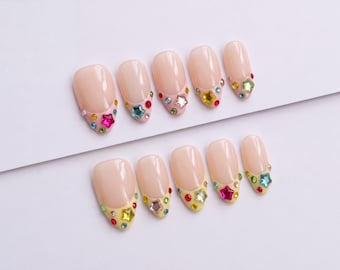 Pinke und gelbe French-Tip-Press-On-Nägel mit bunten Strasssternen