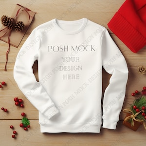 Może przedstawiać: Biała bluza z długim rękawem z napisem "POSH MOCK YOUR DESIGN HERE" na drewnianej powierzchni z czerwonymi jagodami i czerwonym wełnianym berecikiem.
