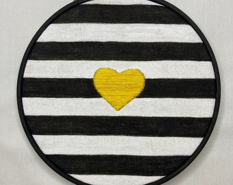 Hand Made wall art. Embroidered Yellow heart on black and white fabric. Framed in a black bamboo hoop.