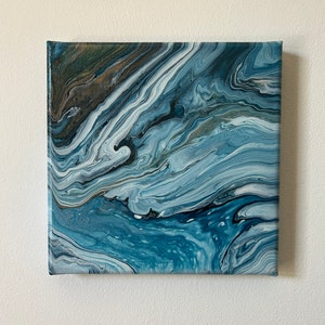 Puede incluir: Pintura abstracta sobre lienzo con colores azules, blancos y grises que se arremolinan. La pintura tiene un aspecto fluido y org&aacute;nico, que recuerda al agua o las nubes.
