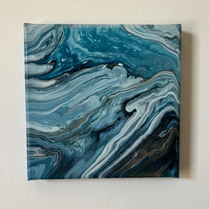 Puede incluir: Pintura abstracta sobre lienzo con pintura azul, blanca y negra que se arremolina creando un efecto de m&aacute;rmol.