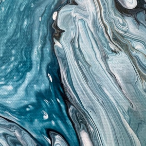 Puede incluir: Pintura abstracta con pintura azul, blanca y negra que gira. La pintura crea un efecto de m&aacute;rmol.