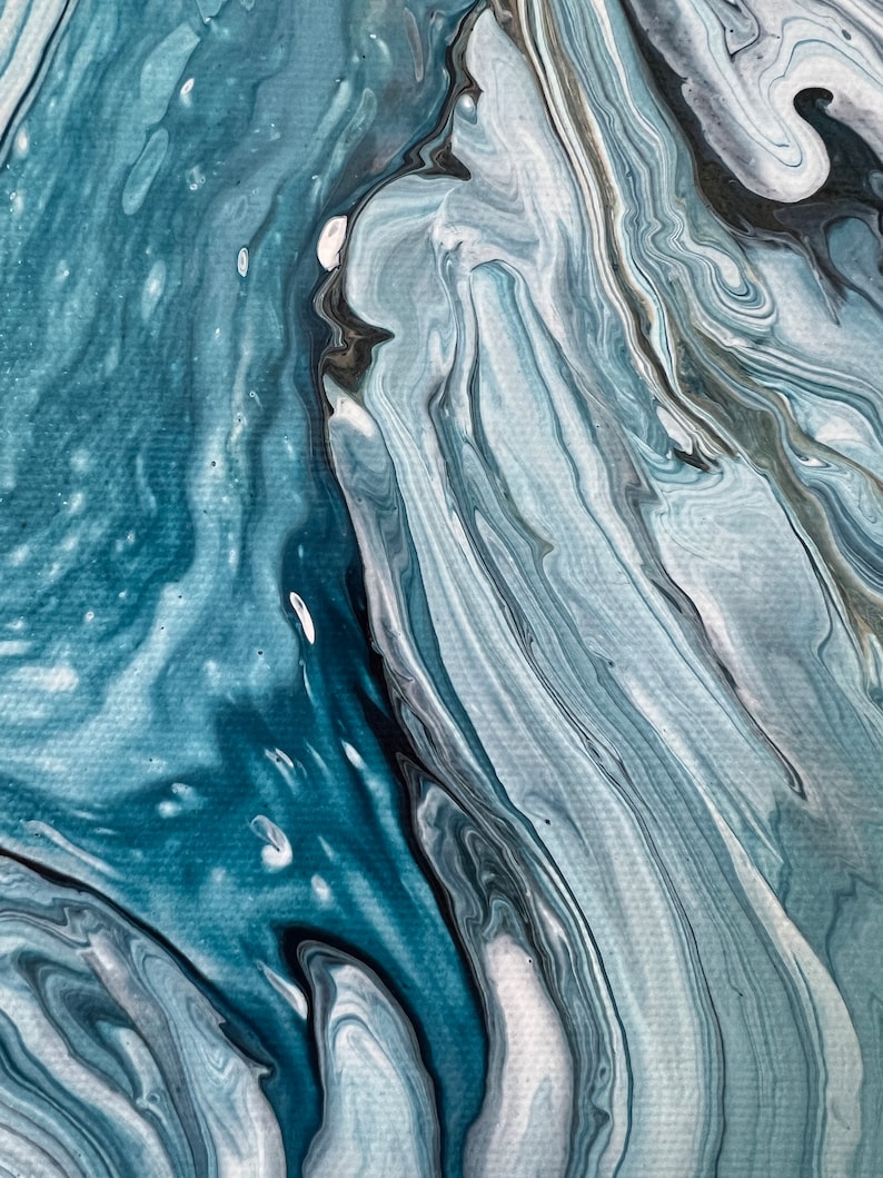 Puede incluir: Pintura abstracta con pintura azul, blanca y negra que gira. La pintura crea un efecto de m&aacute;rmol.
