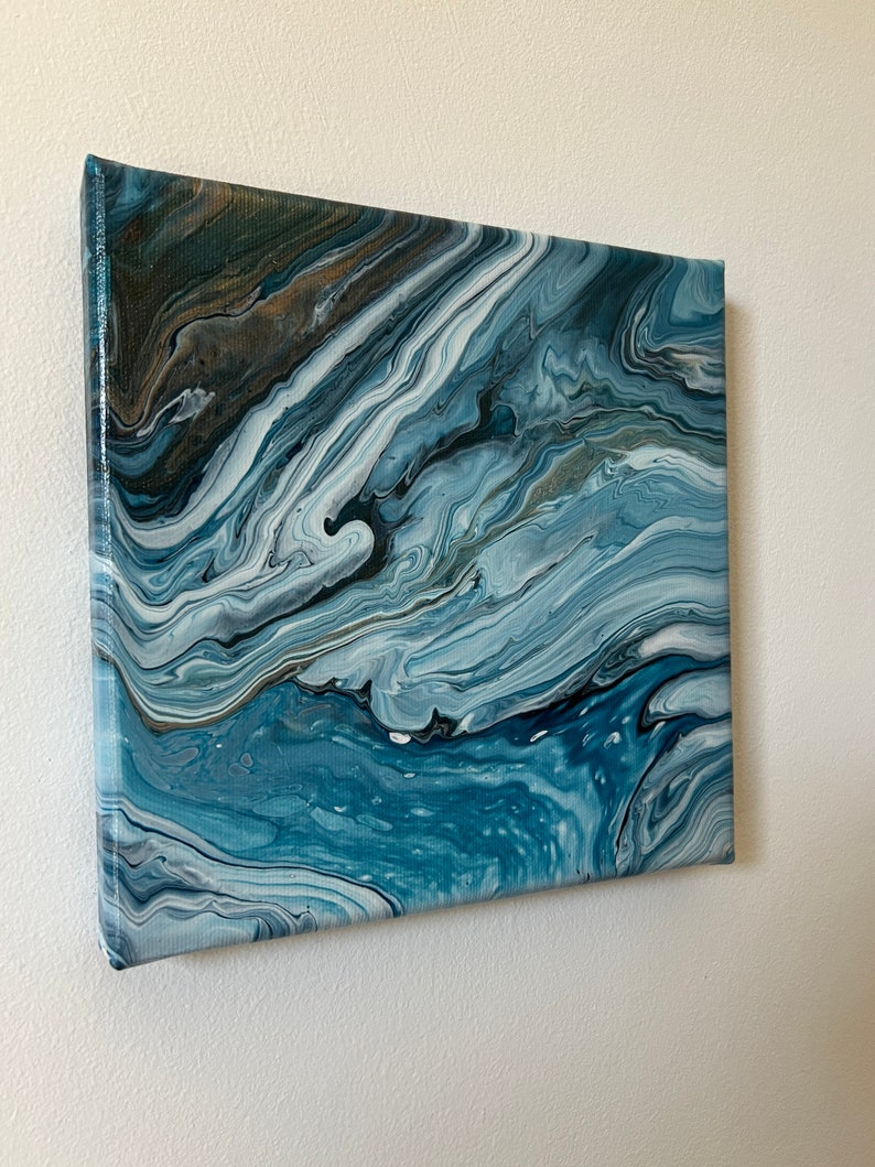 Puede incluir: Pintura abstracta sobre lienzo con colores azules, blancos y grises en espiral. La pintura tiene un efecto marmoleado.