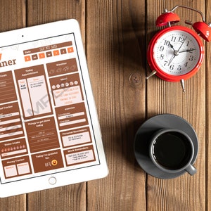 May include: A digital daily planner displayed on a white tablet, with a red alarm clock and a cup of coffee on a wooden surface. The planner includes sections for goals, appointments, and mood tracking. The clock shows 10:10.
